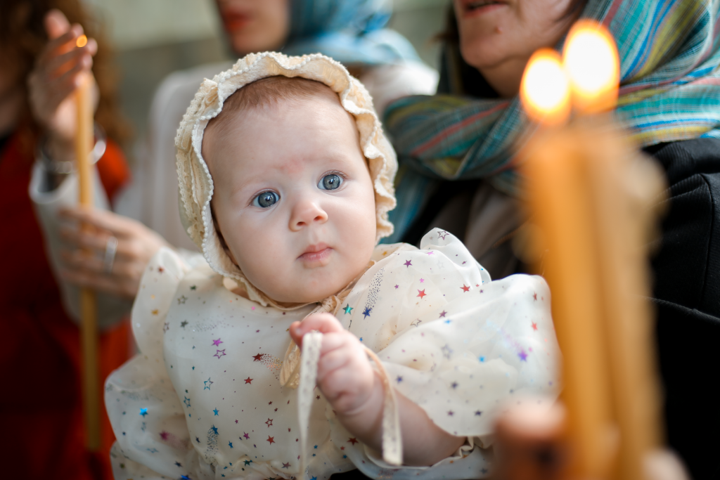 Bébé lors de la cérémonie de son baptême, entouré de bougies