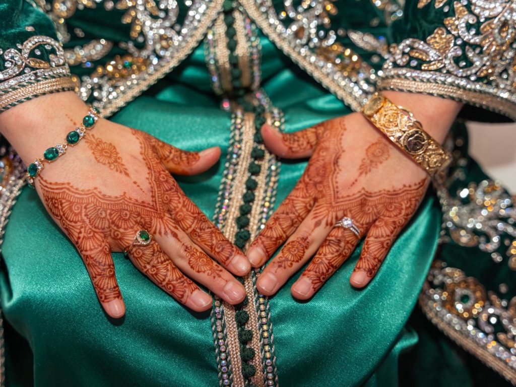 Mains décorées au henné et tenue traditionnelle verte et dorée