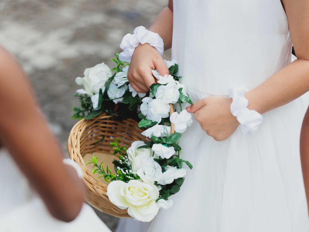 Enfants d'honneur tenant des paniers en osier décorés de roses blanches