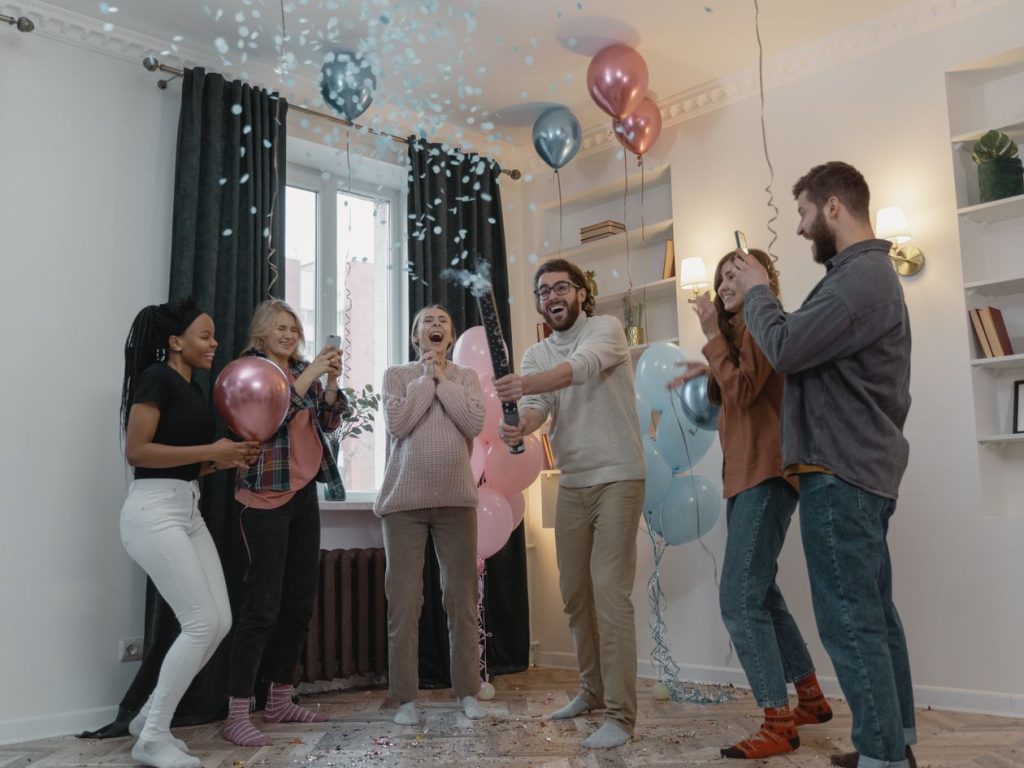 Amis célébrant une gender reveal avec ballons et confettis