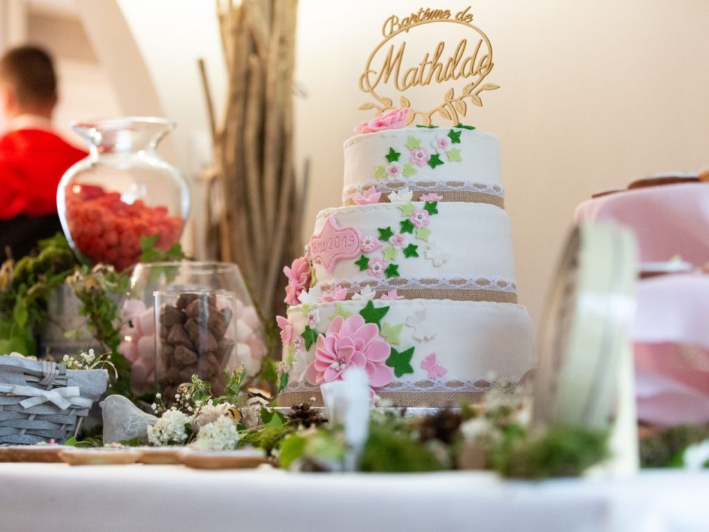 Gâteau à trois étages décoré de fleurs pour une fête de baptême