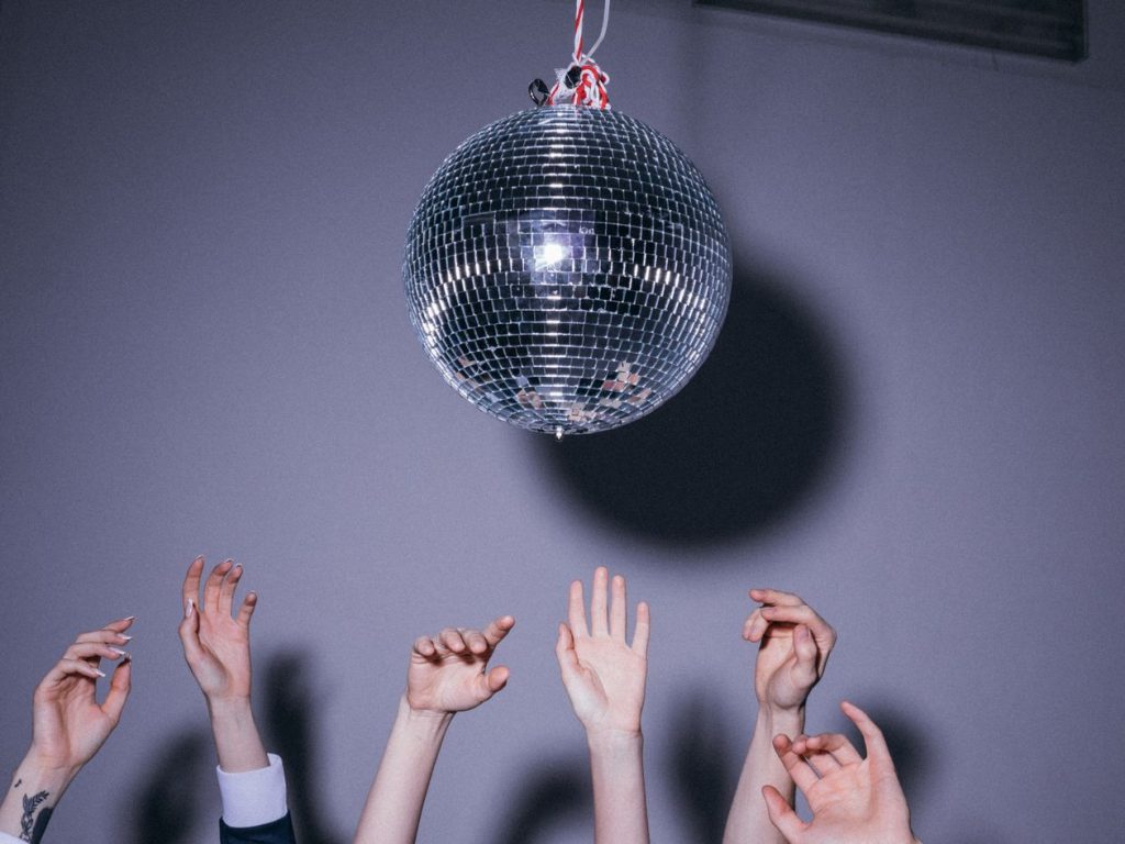 Invités tendant la main vers une boule à facettes