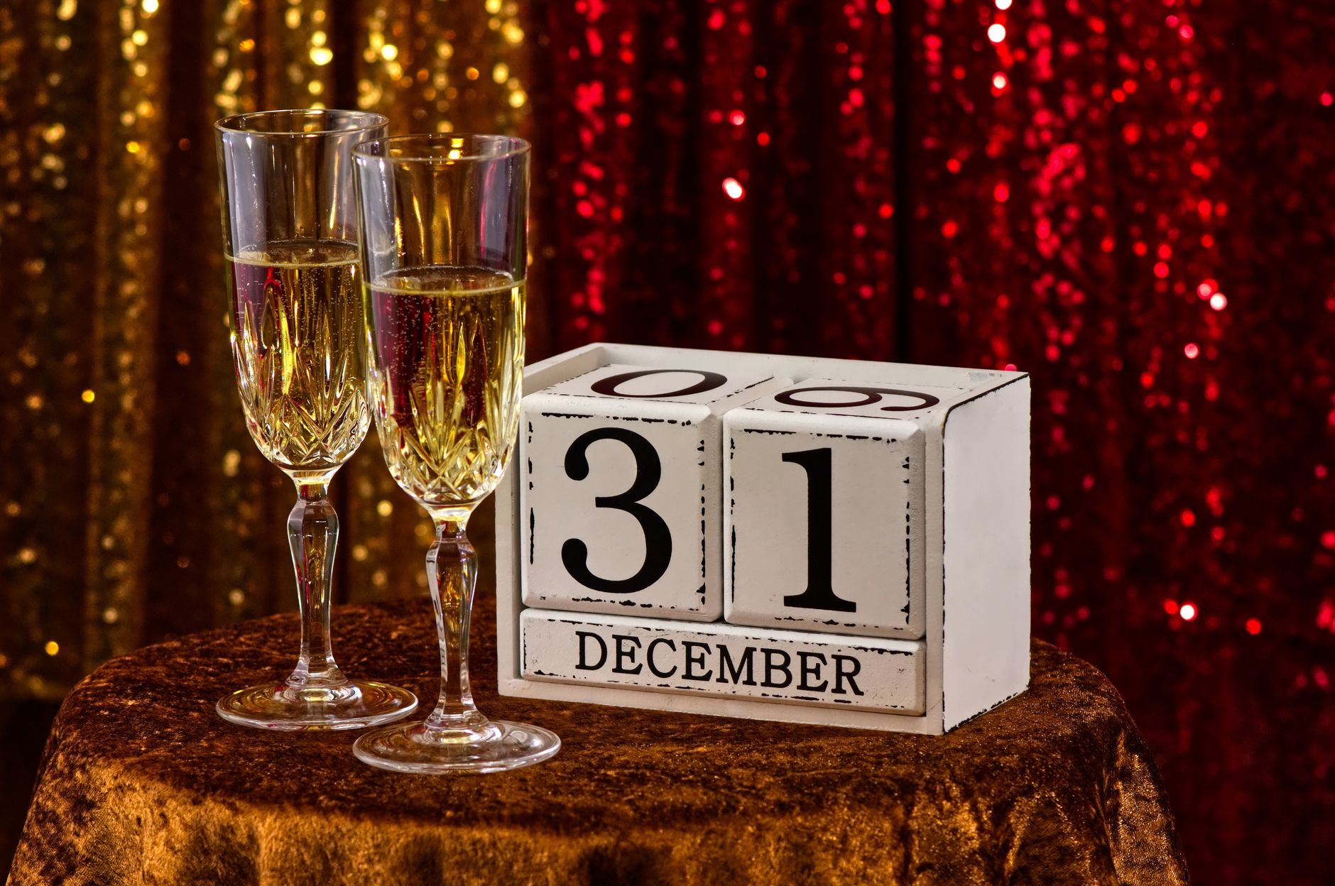 Deux flûtes de champagne à côté d'un calendrier en bois indiquant le 31 décembre